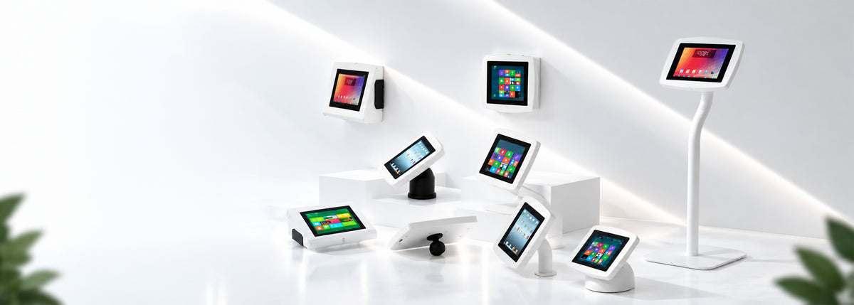 White tablet wall mounts, desktop stands and a floor stand holding iPad, Android and Windows tablets