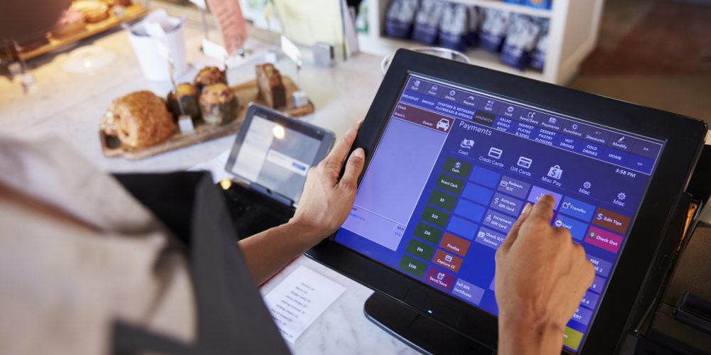 Close-up of a hand using a point-of-sale app on a tablet screen with order and payment options